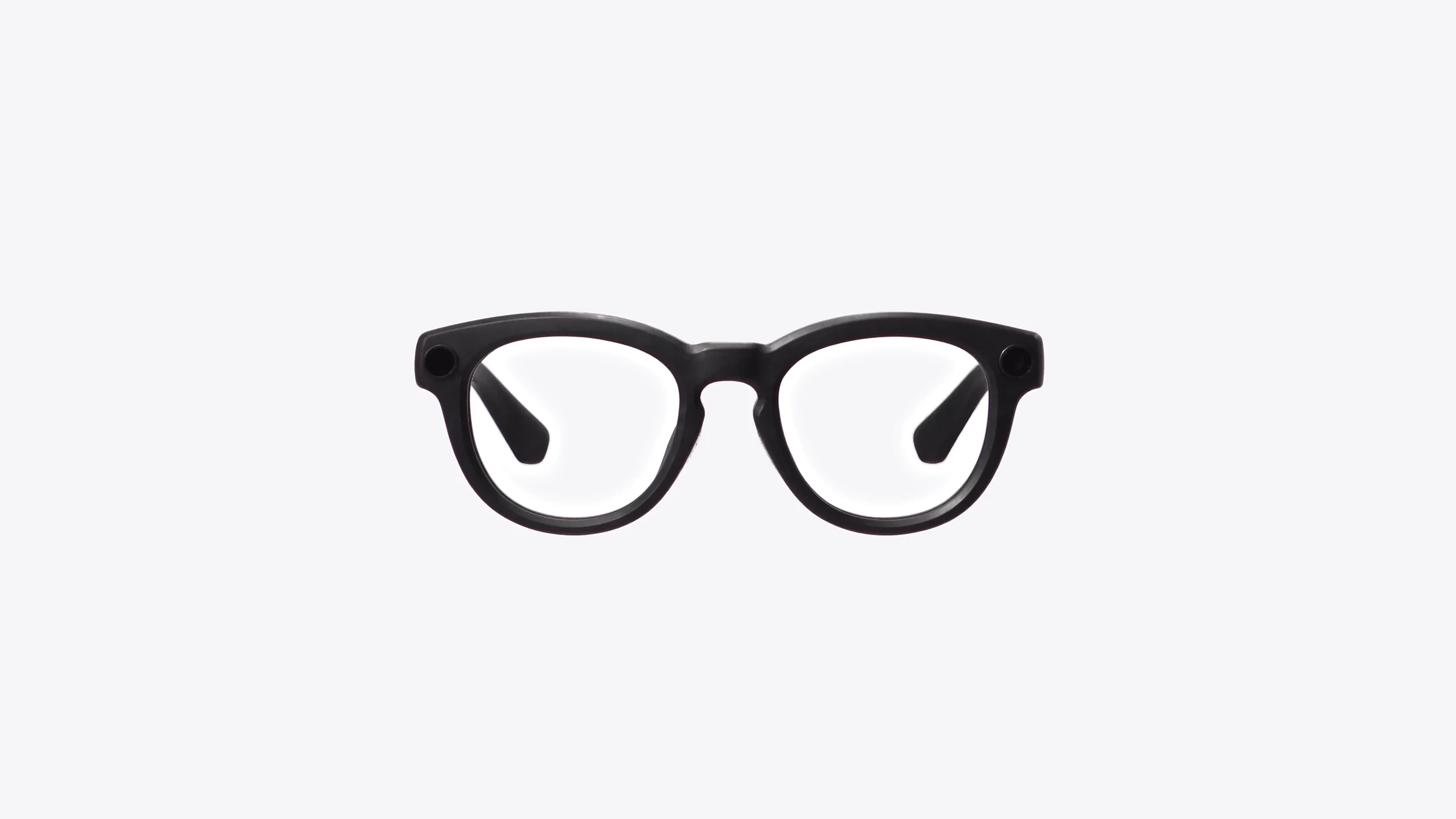 Neurodrishti Smartglasses from the front: a matt black frame with clear lenses and a small round camera at each front corner